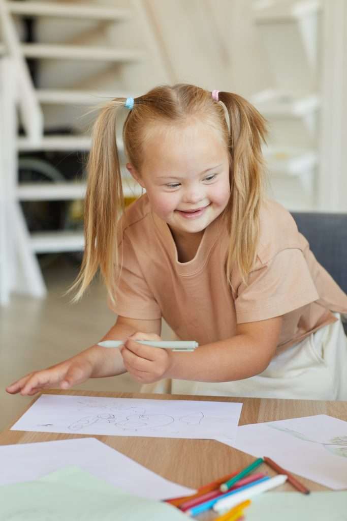 vertical,portrait,of,cute,blonde,girl,with,down,syndrome,drawing